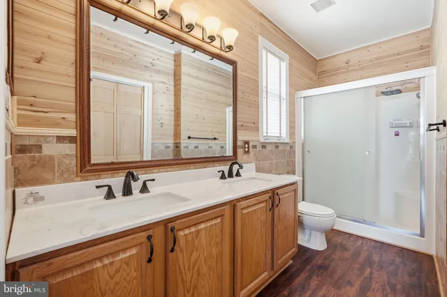 a view of a hallway with wooden floor closet and windows