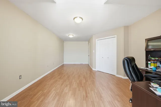 a view of an empty room with wooden floor and windows