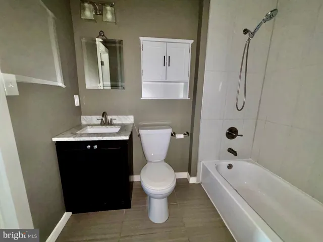 an empty room with wooden floor and fan