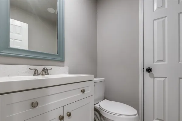 a bathroom with a toilet sink vanity and mirror