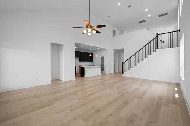 a view of empty room with wooden floor and ceiling fan