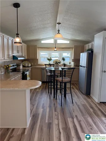 a kitchen with stainless steel appliances a dining table chairs stove refrigerator and cabinets