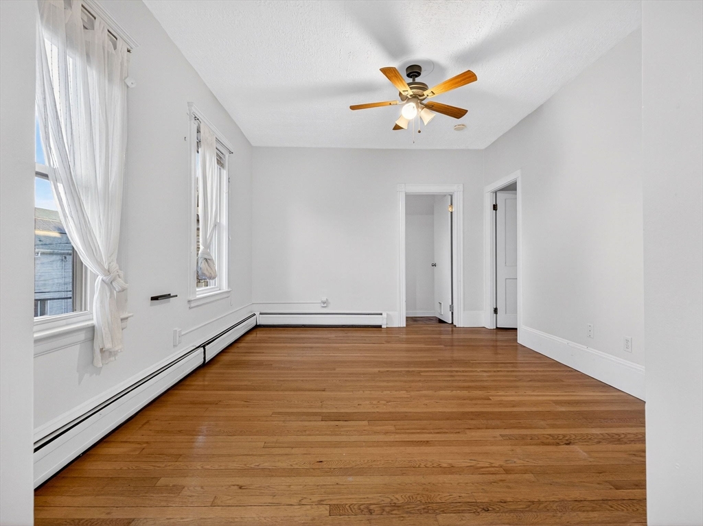 12 Braemore Road, Unit 2 Medford, MA 02155 - Photo 15 of 24 a view of an empty room with window and wooden floor