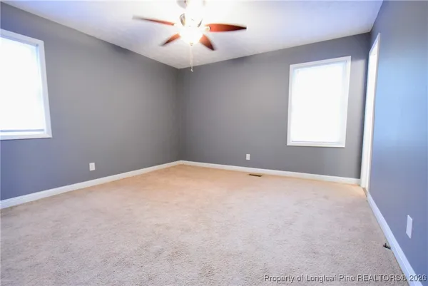 an empty room with a window and a fan
