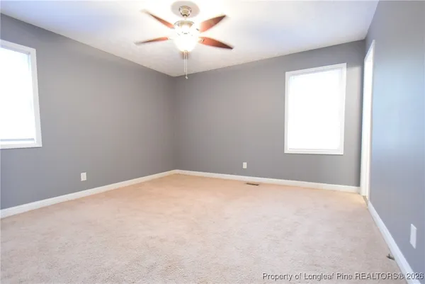 an empty room with a window and a fan