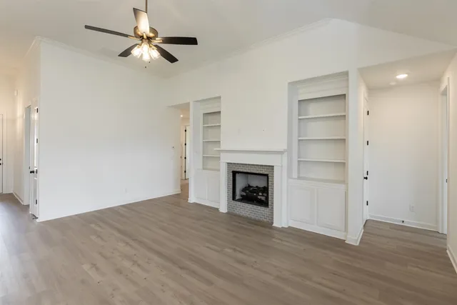 an empty room with wooden floor fan and windows