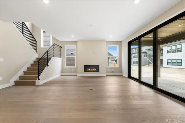 a view of an empty room with wooden floor fireplace and windows