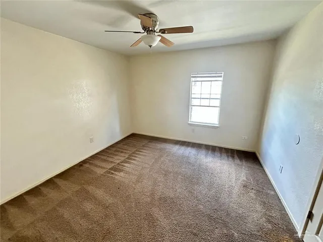 an empty room with a window and a ceiling fan