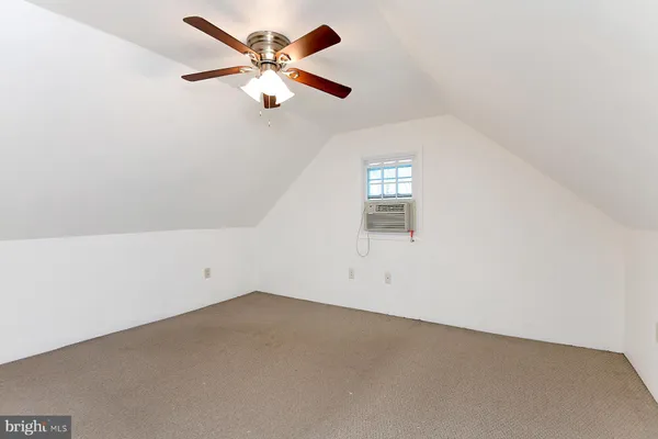 an empty room with a chandelier fan and windows