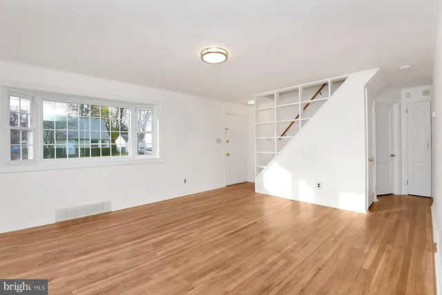 a view of an empty room with wooden floor and windows