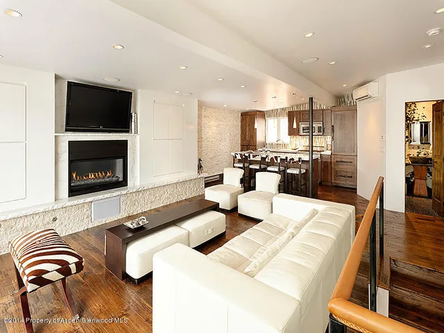 a living room with stainless steel appliances furniture a rug and a kitchen view