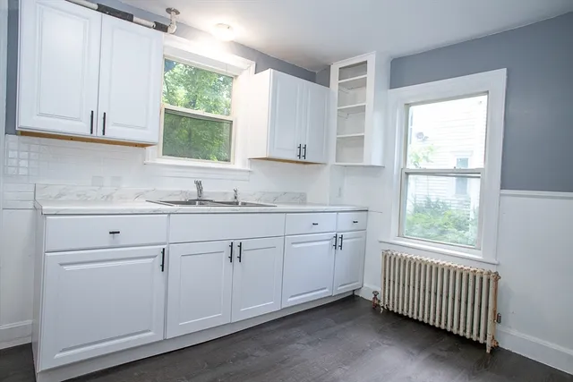 a kitchen with granite countertop white cabinets window and sink