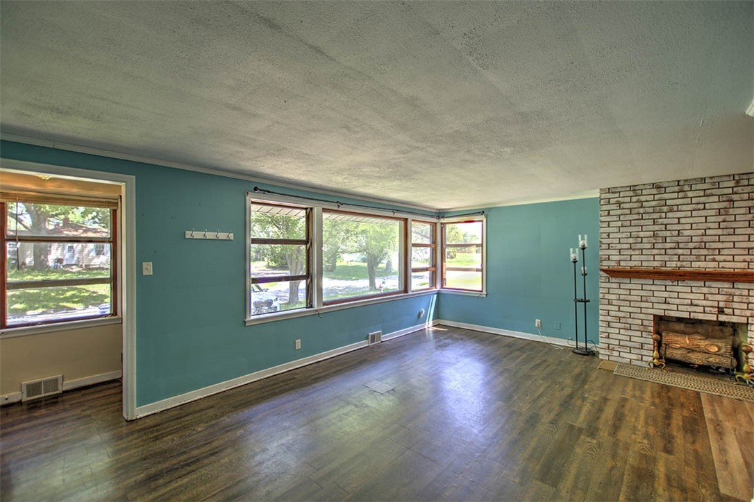 2133 East Moore Street Decatur, IL 62521 - Photo 4 of 26 an empty room with wooden floor fireplace and windows