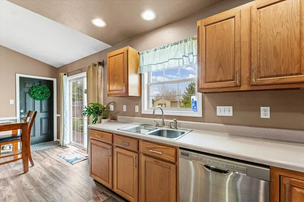 a kitchen with stainless steel appliances granite countertop a sink a counter space and wooden floor