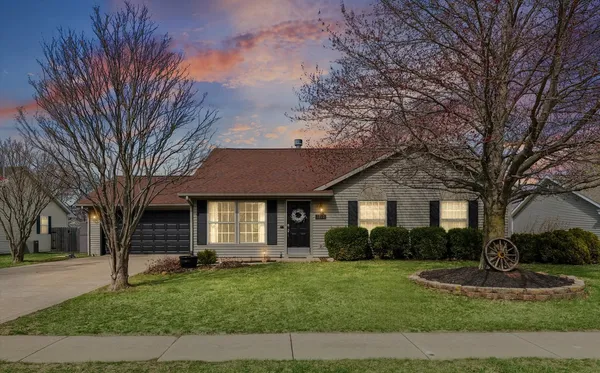 a front view of a house with a garden and trees