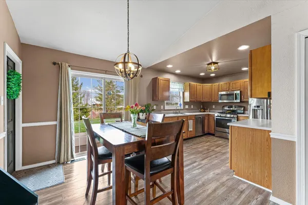 a dining room with wooden floor a chandelier a wooden table and chairs