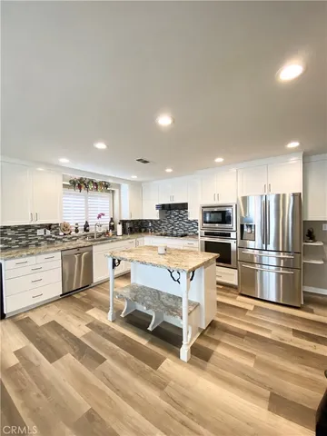 a kitchen with stainless steel appliances kitchen island granite countertop a stove a sink and a refrigerator
