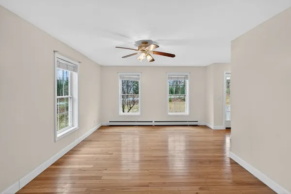 a view of an empty room with a window and wooden floor
