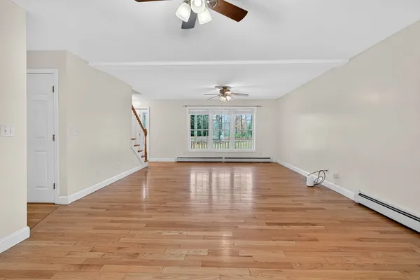 an empty room with wooden floor fan and windows