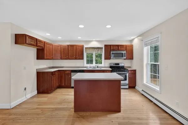 a kitchen with stainless steel appliances granite countertop a stove top oven a sink dishwasher and a microwave oven on the wooden floor