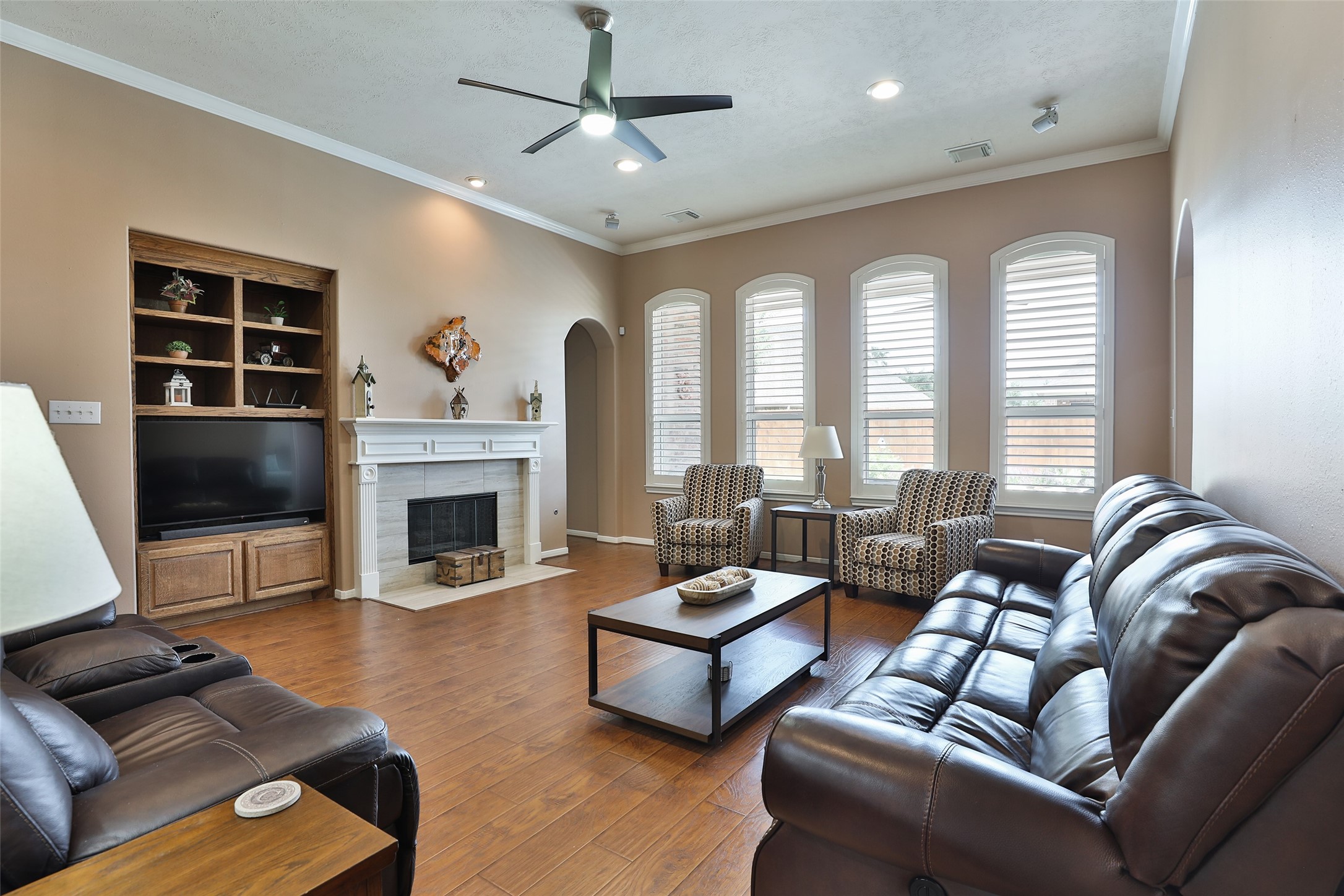 20519 Windrose Bend Drive Spring, TX 77379 - Photo 17 of 37 This spacious living area features a custom gaslog fireplace accented by upgraded tile, elegant crown molding, integrated surround sound, and built-in cabinetry. Plantation shutters offer adjustable privacy while beautifully framing views of the backyard oasis.