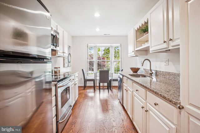 a kitchen with granite countertop a sink a counter space appliances and cabinets