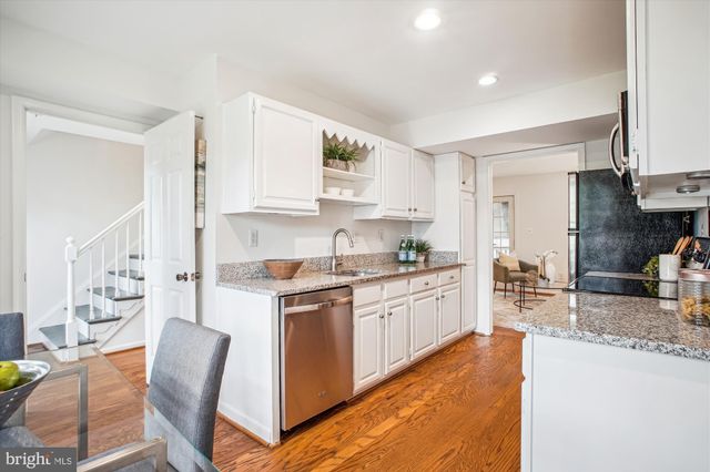 a kitchen with stainless steel appliances granite countertop a stove top oven a sink a dining table and chairs with wooden floor