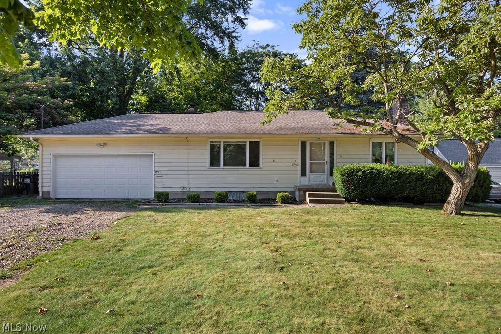 Ranch-style residence featuring light-colored siding, a two-car garage, and a covered front entry
