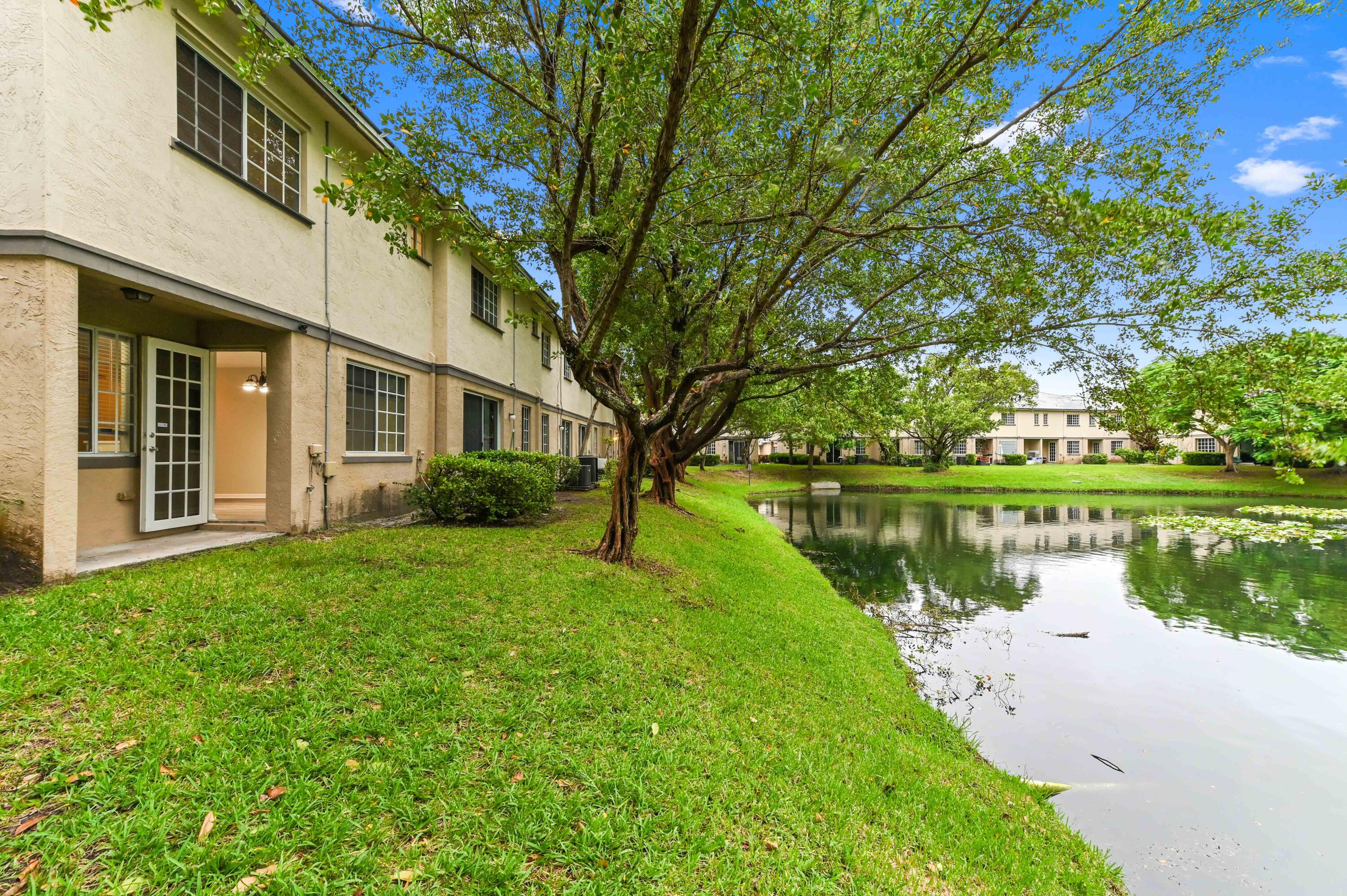 975 Tortuga Drive Riviera Beach, FL 33404 - Photo 28 of 29 a view of a house with a yard next to a lake