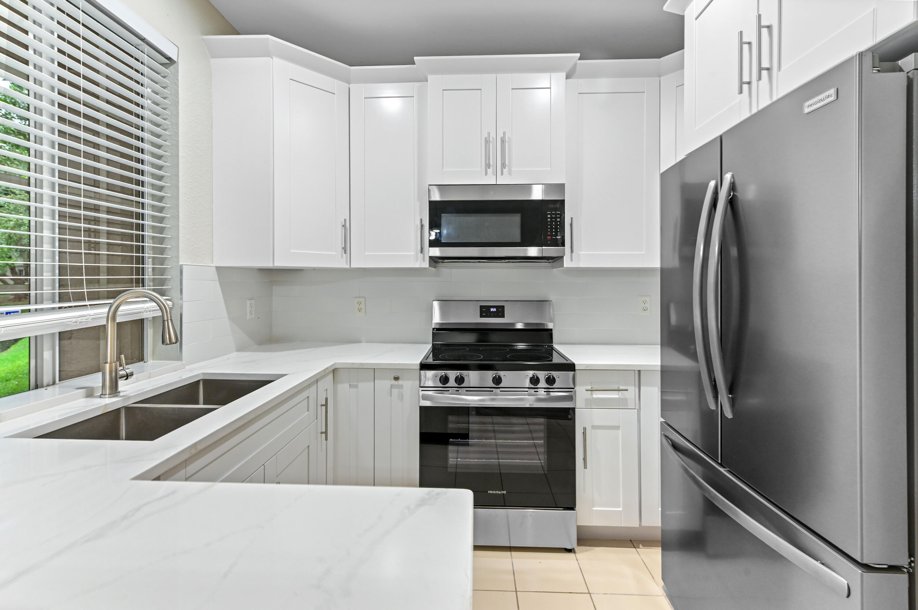 975 Tortuga Drive Riviera Beach, FL 33404 - Photo 10 of 29 a kitchen with stainless steel appliances granite countertop a refrigerator sink and stove
