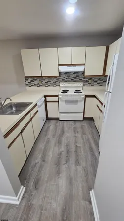 a kitchen with a sink a stove cabinets and a wooden floor
