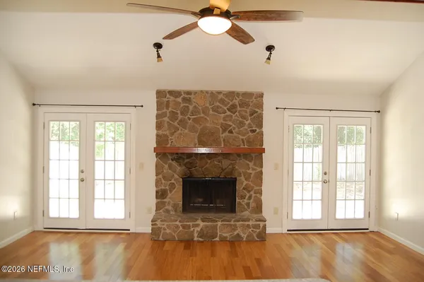 a view of an empty room with wooden floor and a window