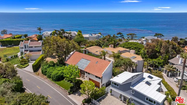an aerial view of ocean and residential houses with outdoor space
