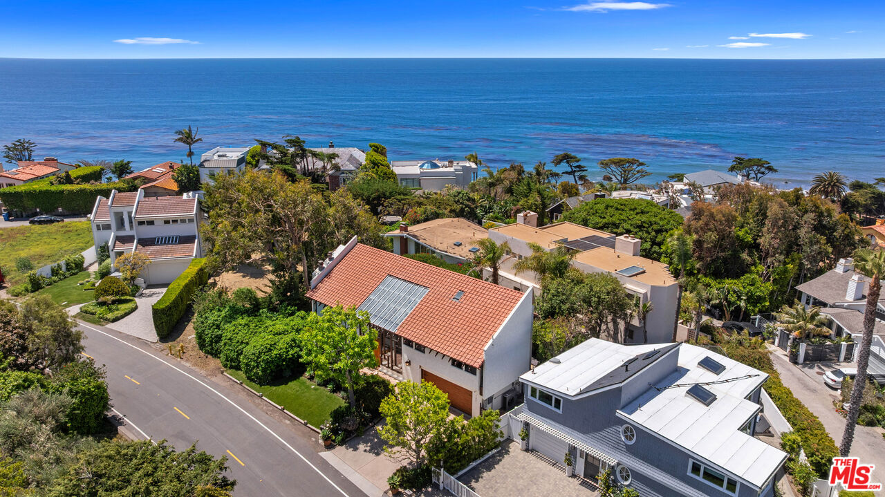 an aerial view of ocean and residential houses with outdoor space