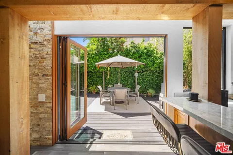 a view of a patio with a dining table and chairs under an umbrella with a small yard