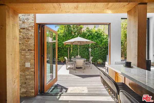 a view of a patio with a dining table and chairs under an umbrella with a small yard