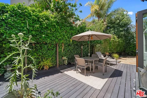 a view of a roof deck with table and chairs under an umbrella with wooden floor