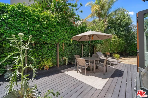 a view of a roof deck with table and chairs under an umbrella with wooden floor