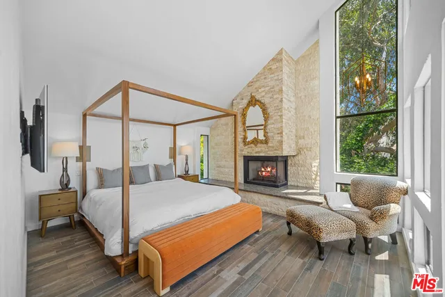 a bedroom with a bed a fireplace and a large window