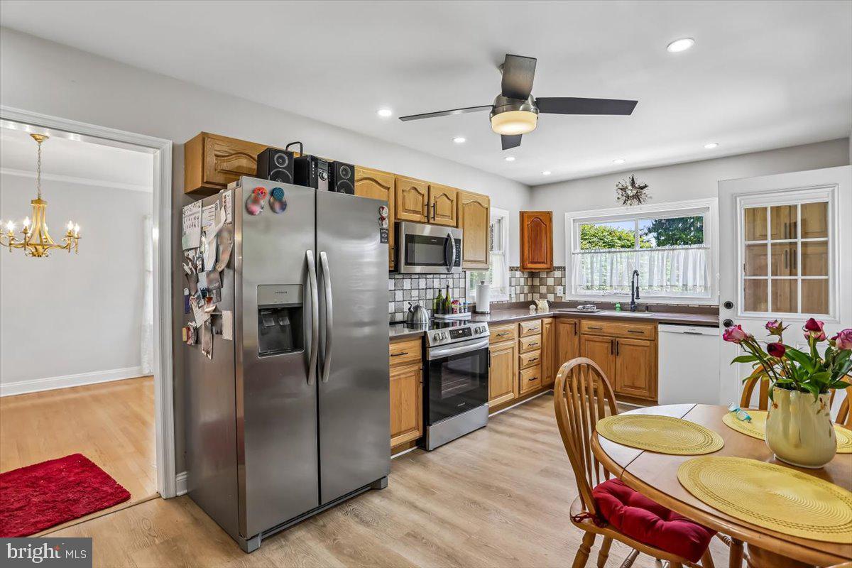 321 North 3rd Street Oakland, MD 21550 - Photo 15 of 48 a kitchen with stainless steel appliances granite countertop a refrigerator a stove a sink a dining table and chairs with wooden floor