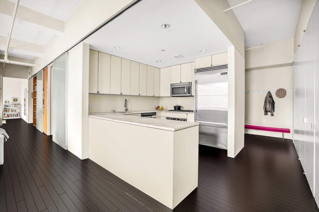 11 West 30th Street, Unit 8F Manhattan, NY 10001 - Photo 5 of 20 a kitchen with stainless steel appliances white cabinets and wooden floor