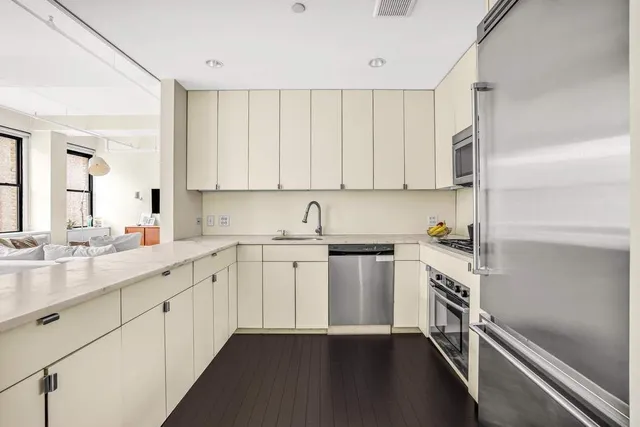 a kitchen with stainless steel appliances white cabinets and wooden floor