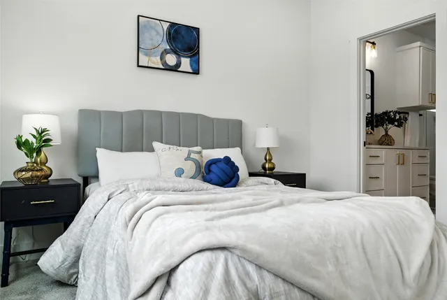 a bedroom with a bed and a lamp on dresser