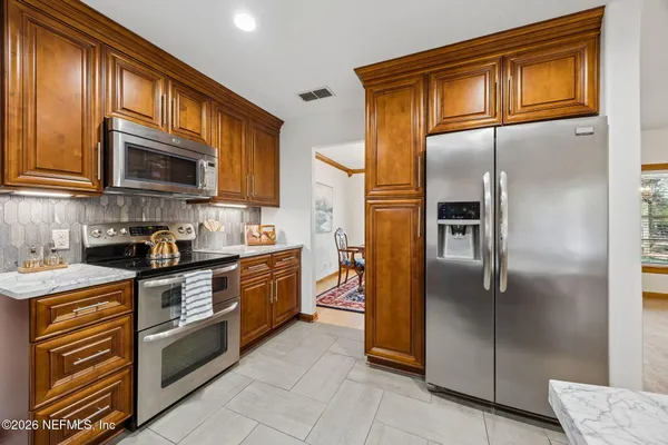 a kitchen with stainless steel appliances granite countertop a refrigerator a stove top oven and a sink