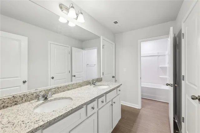a bathroom with a granite countertop double vanity sink and a mirror
