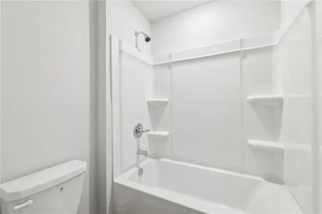 a white bath tub sitting next to a white toilet and vanity