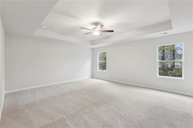 an empty room with windows and fan chandelier fan