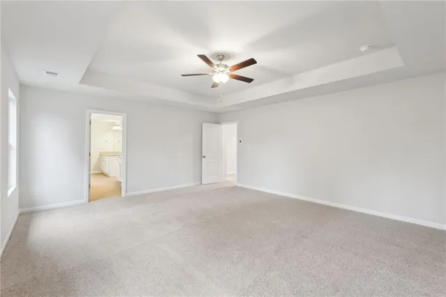 an empty room with a chandelier fan and windows