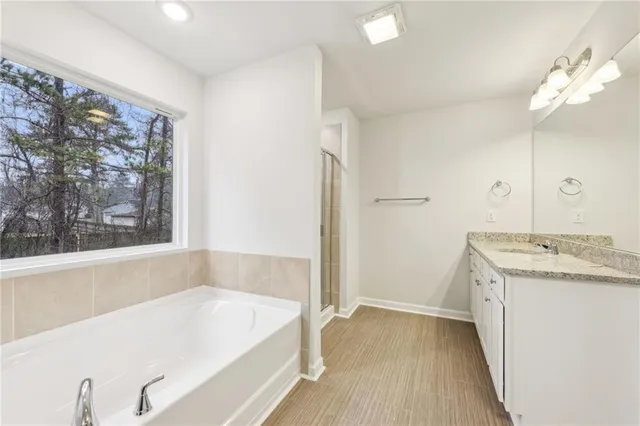 a bathroom with a tub a sink and a large mirror