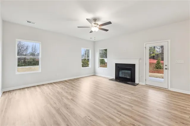 a view of an empty room with wooden floor fireplace and a window